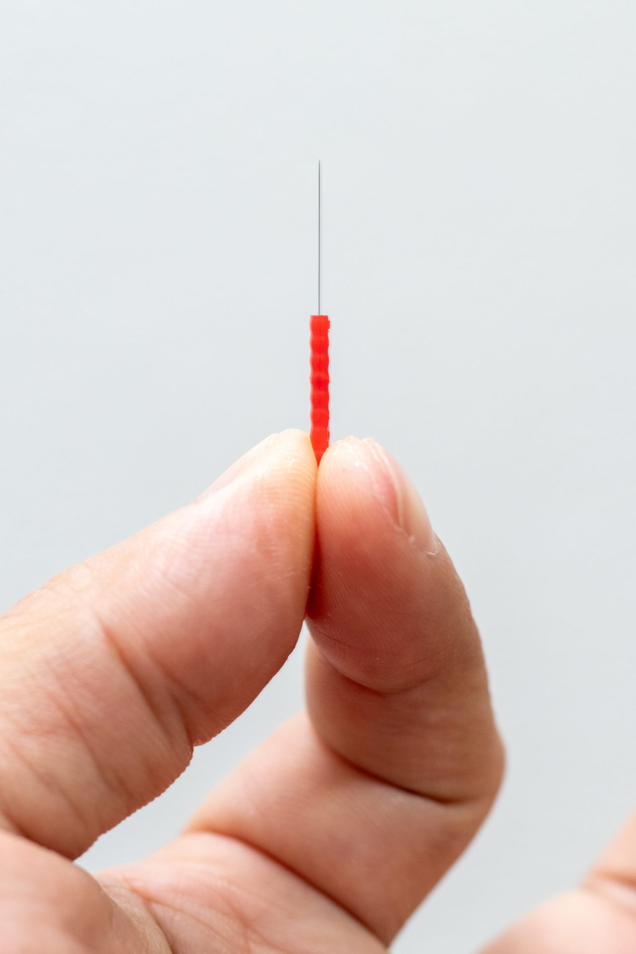 指でつまんだ鍼のアップ・髪の毛ほどの細さ